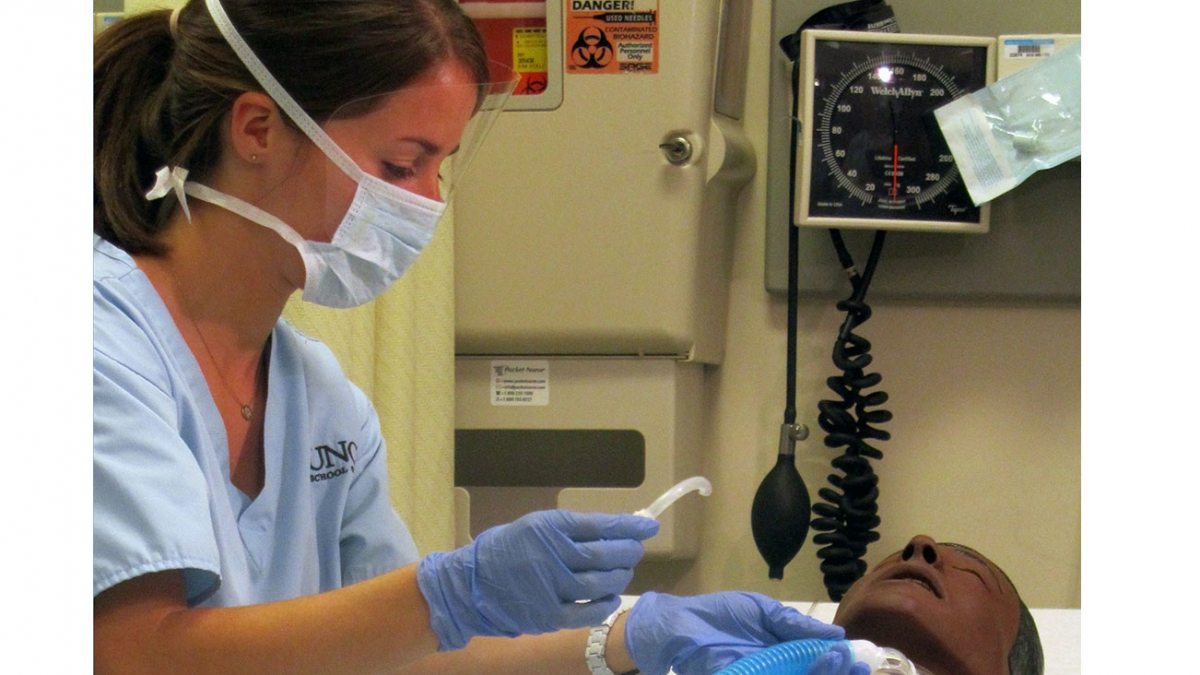 A nursing student works on a mock patient.