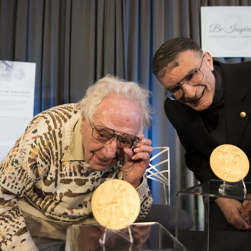 Oliver Smithes and Aziz Sancar look at their Nobel Prize Medals.