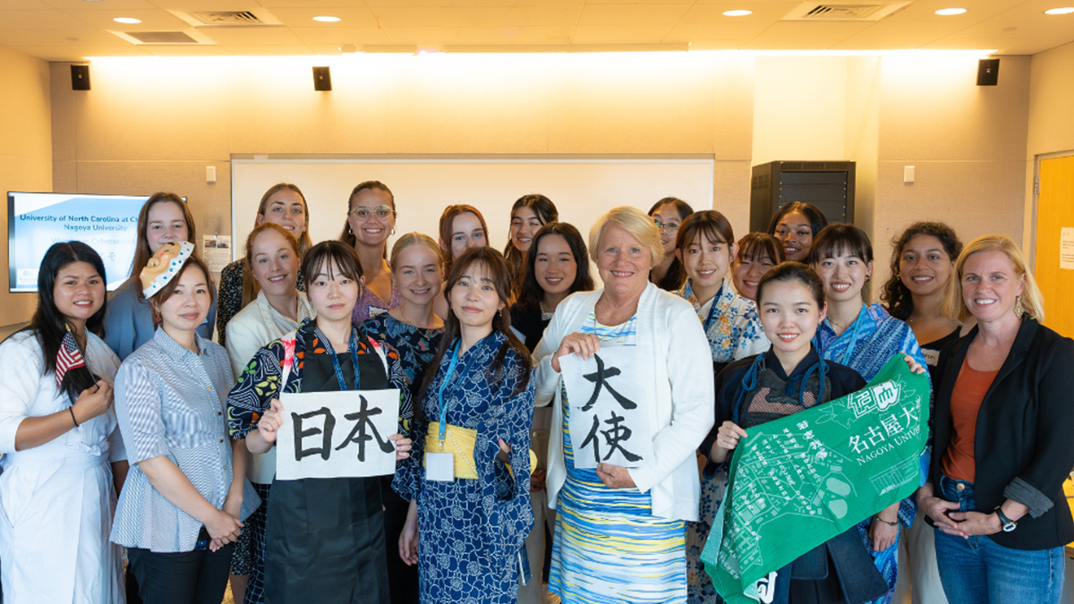 Large group of women posing with various signs.
