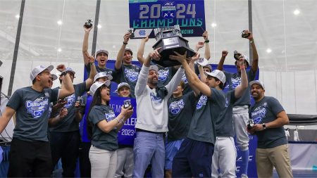 The Carolina men's fencing team celebrating as a group and lifting a trophy after winning the conference championship.
