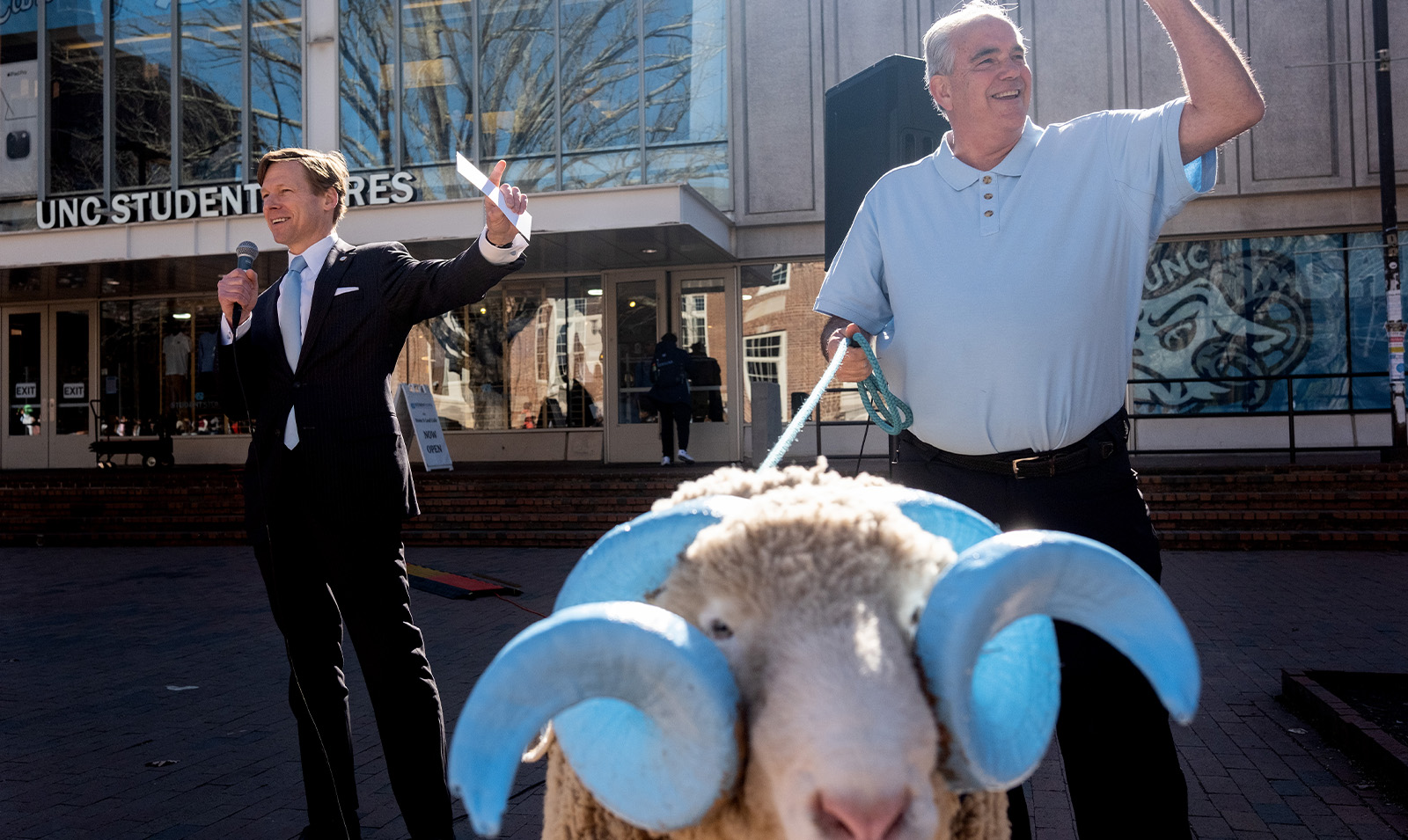 Interim Chancellor Lee H. Roberts giving a speech while a handler holds onto a leash next to a live ram mascot, Rameses.